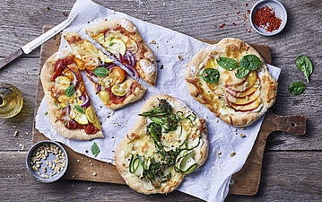 Vegetarische Mini-Pizzen mit Zucchini-Brokkoli-Mix und bunten Tomaten