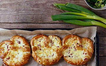 Überbackener Brezel-Snack mit Schinkenwürfeln, Käse und Zwiebelquark